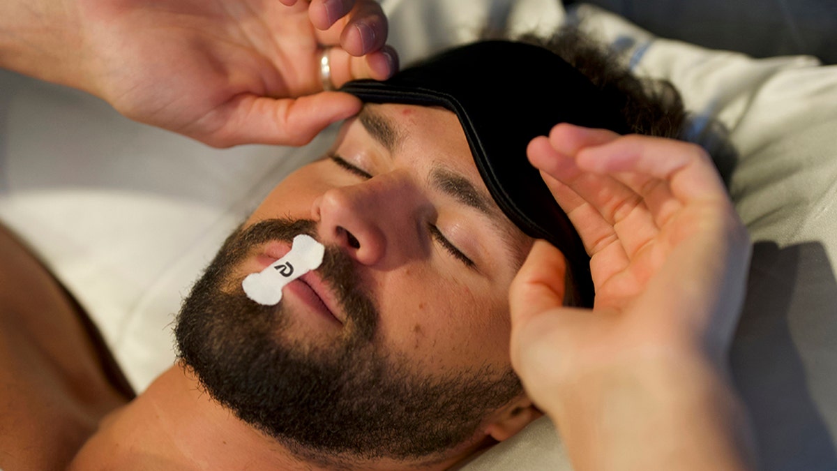 Man gets ready to sleep with tape mouth on top